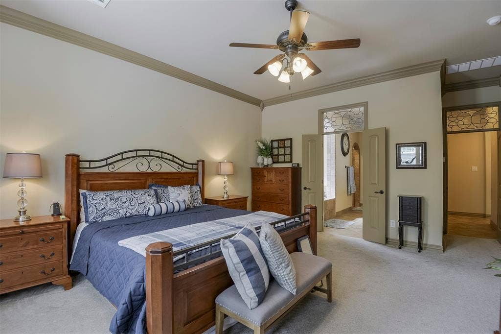 Spacious sleeping area featuring crown molding, a ceiling fan with integrated lighting, and carpet flooring