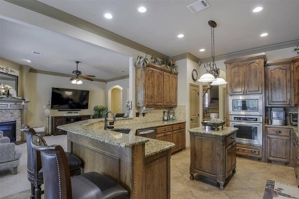 Kitchen featuring wood cabinetry, granite countertops, tile flooring, recessed lighting, and stainless steel built-in appliances