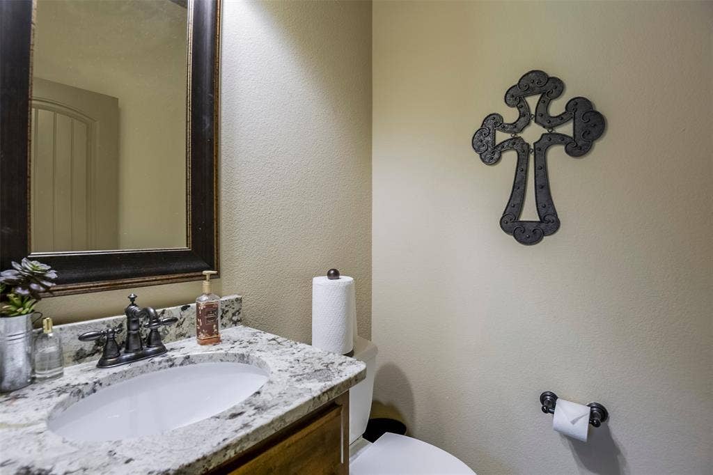 Ensuite bath featuring a countertop with an integrated sink, a framed mirror, and a wall-mounted toilet