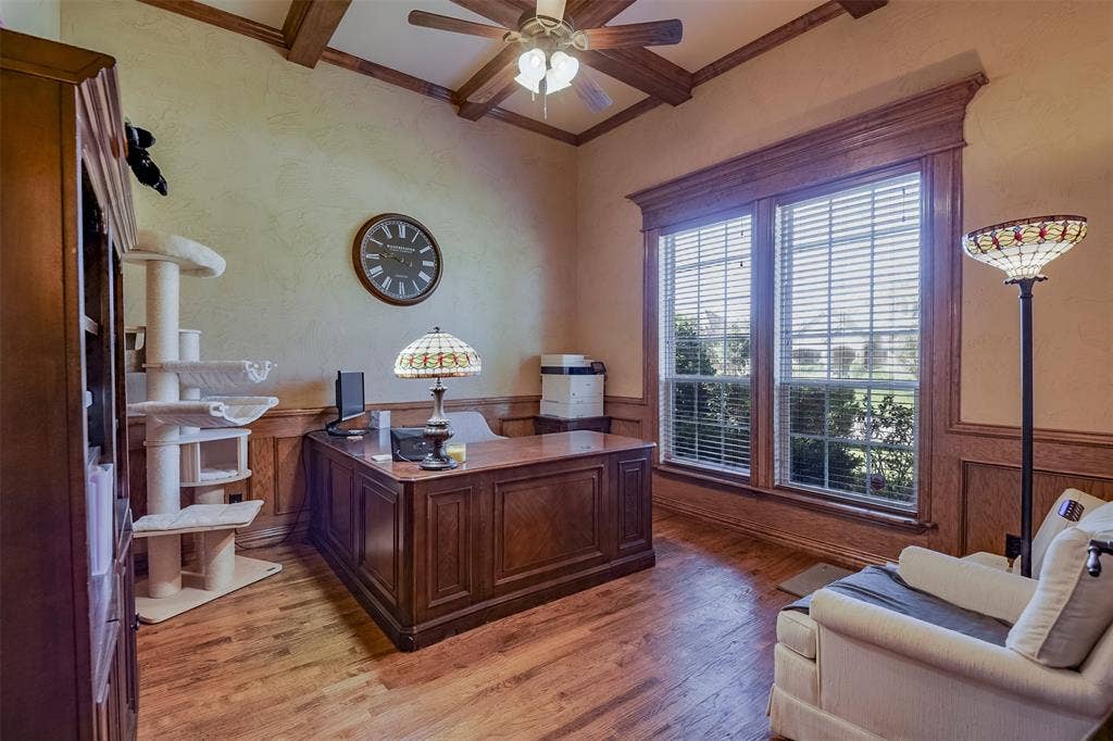 Spacious room featuring wood-finish flooring, wood wall paneling, and a coffered ceiling with a ceiling fan