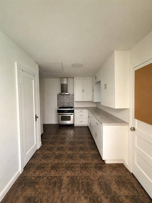 311 S Ebrite Street, Mesquite, TX 75149 Galley kitchen featuring white cabinetry, light-colored countertops, and stainless steel appliances including a range and range hood