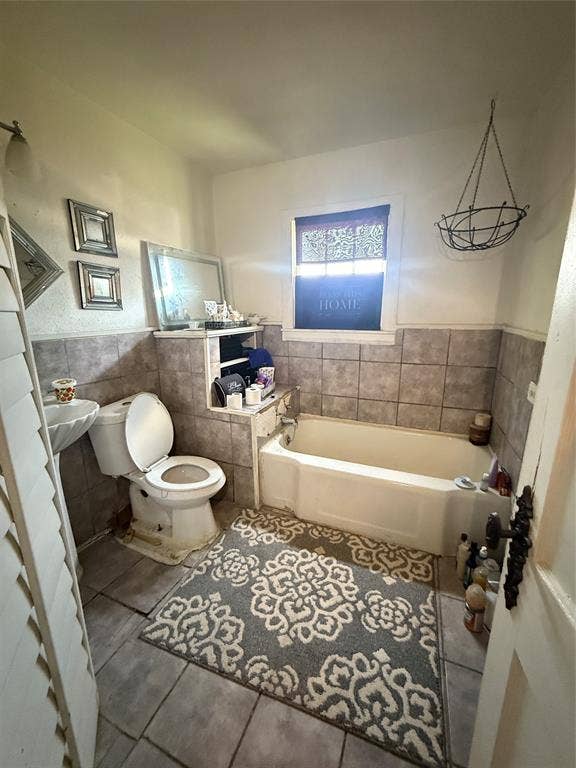 311 S Ebrite Street, Mesquite, TX 75149 Bathroom featuring a built-in bathtub, a pedestal sink, and tiled flooring