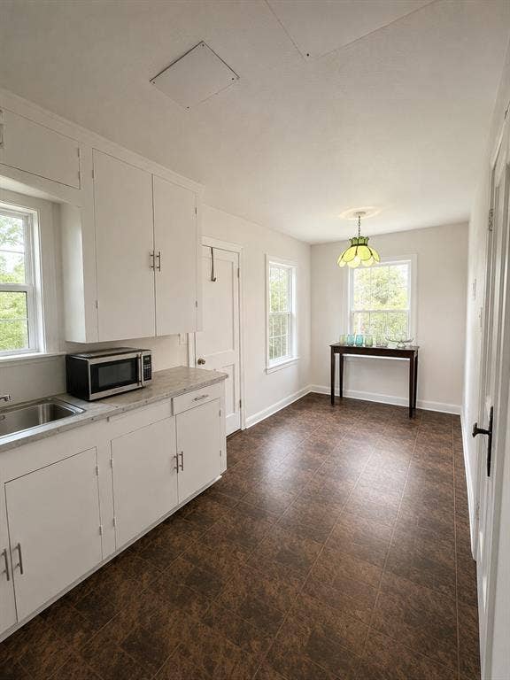 311 S Ebrite Street, Mesquite, TX 75149 Bright kitchen and dining area featuring white cabinetry, a stainless steel sink, light-toned countertops, and large windows providing abundant natural light