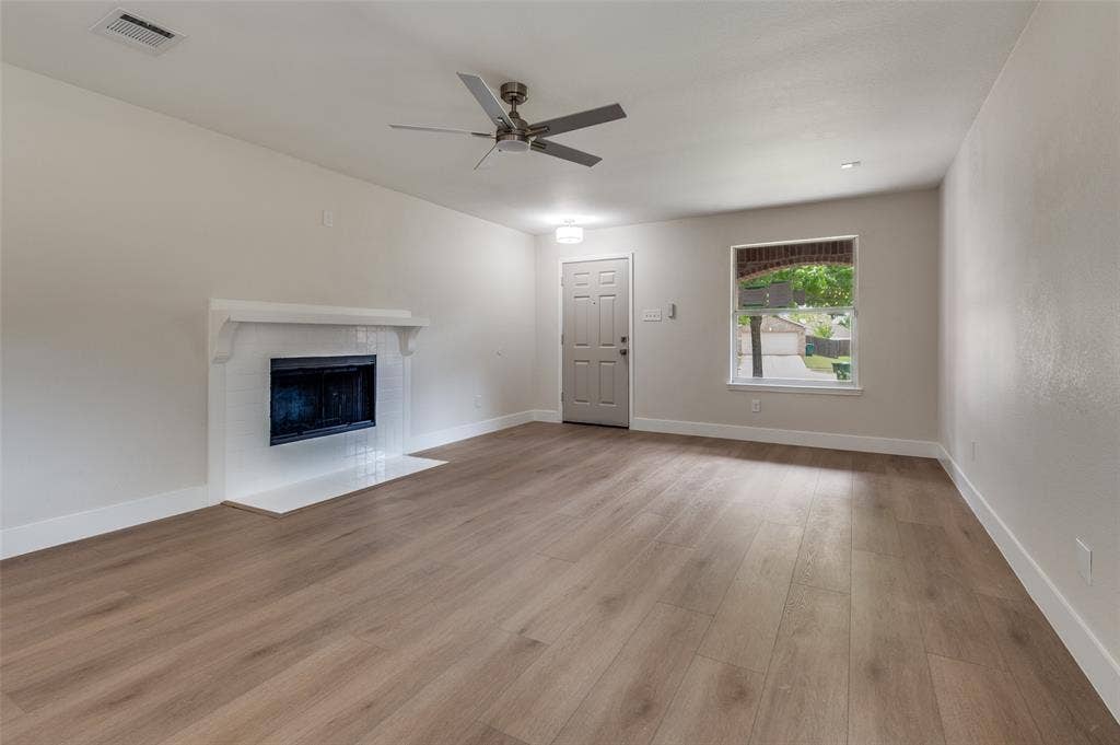 Living space featuring light wood-finish flooring, a white mantel fireplace with a black firebox, a ceiling fan, recessed lighting, and a window offering exterior views