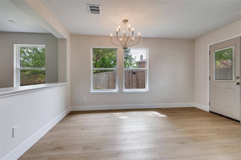 Spacious room featuring light wood-finish flooring and a contemporary chandelier