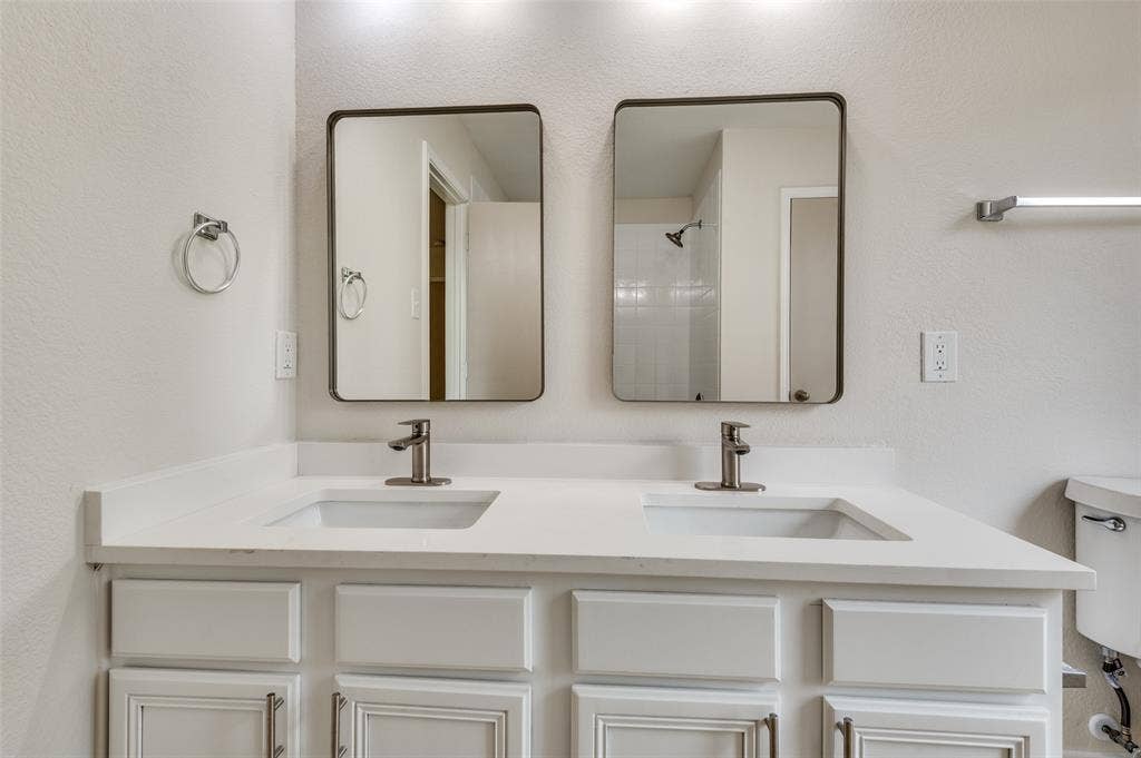 Double vanity with white cabinetry, integrated sinks, brushed nickel faucets, and framed mirrors