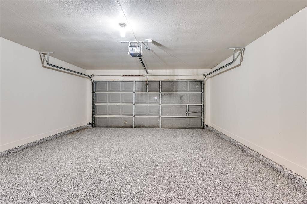 Spacious garage featuring a speckled epoxy floor coating, white painted walls, and an overhead garage door opener