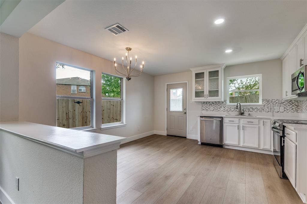 Open-concept living space featuring wood-finish flooring, recessed lighting, and a modern chandelier