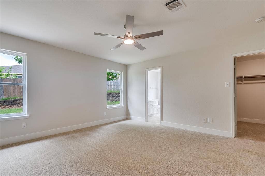 Carpeted interior space featuring light-toned walls and two windows