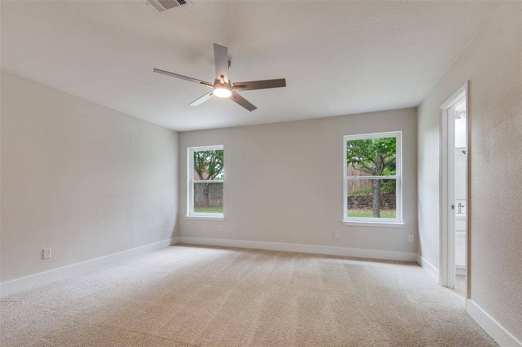 Spacious room featuring neutral carpeting, light-toned walls, and a modern ceiling fan with integrated lighting