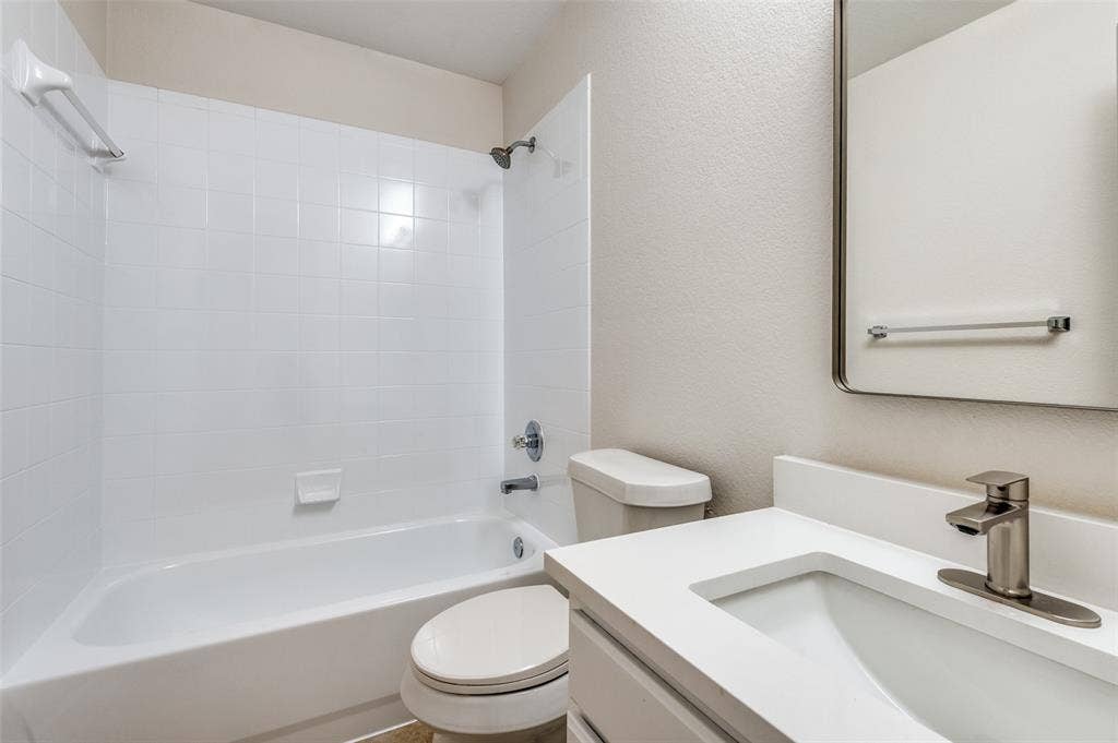 Bathroom featuring a white subway-tile shower surround, a built-in tub, a contemporary vanity with a white countertop, an integrated sink, and a brushed nickel faucet