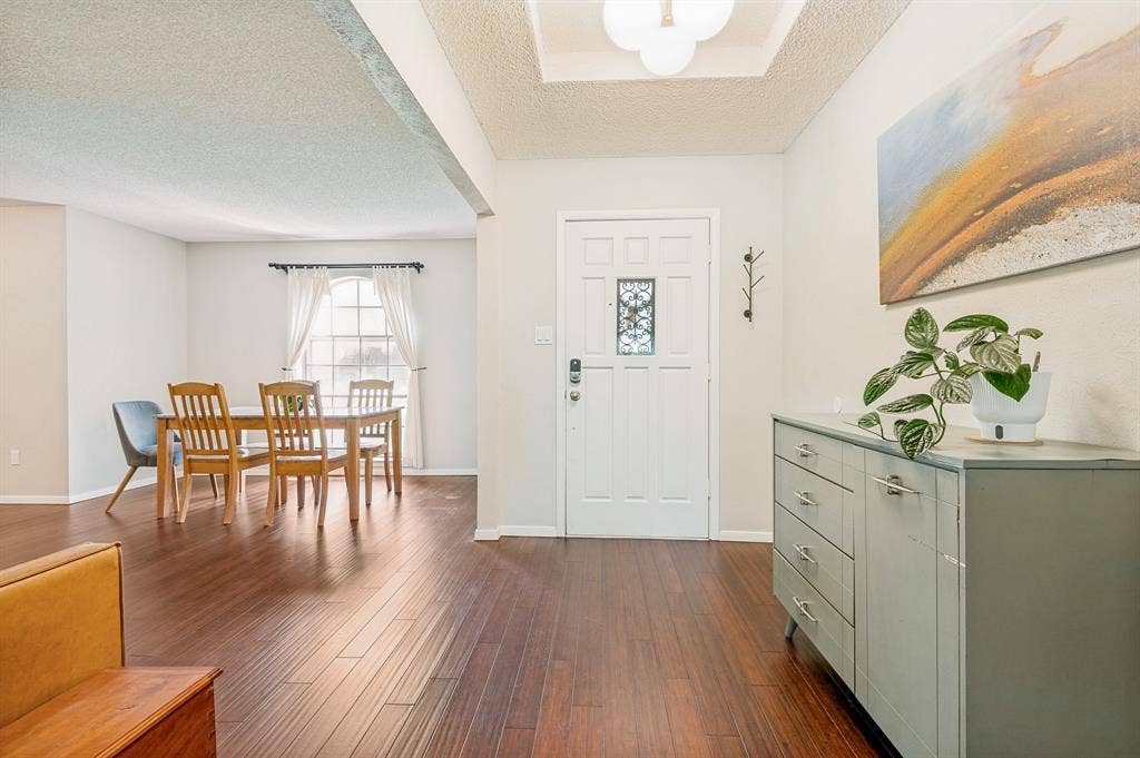 404 Green River Trail, Fort Worth, TX 76103 Entryway featuring wood-finish flooring, a white paneled door with decorative glass inserts, and a recessed ceiling with a contemporary light fixture