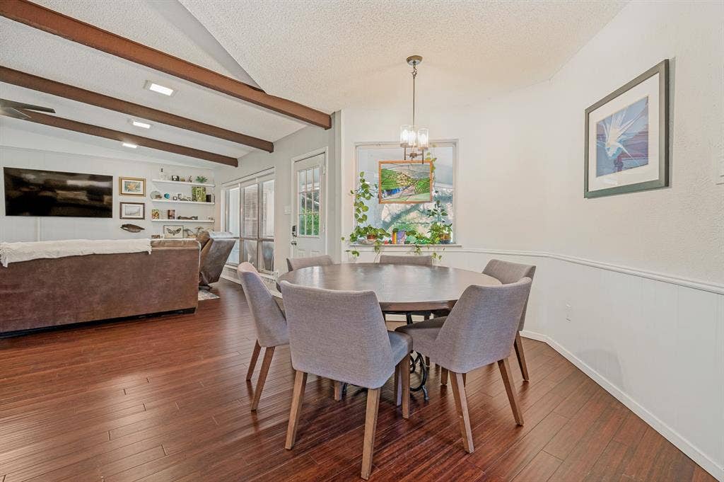 404 Green River Trail, Fort Worth, TX 76103 Open-concept living space featuring wood-finish flooring, vaulted ceilings with exposed beams, built-in shelving, and a dining area with a contemporary chandelier