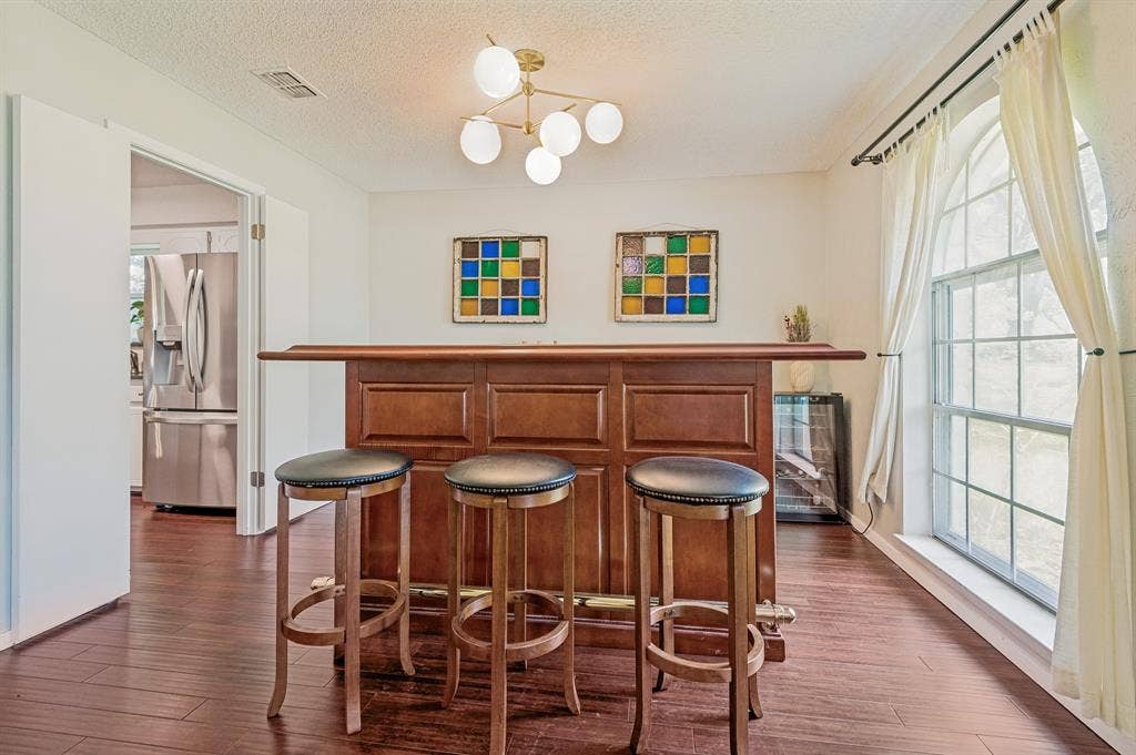 404 Green River Trail, Fort Worth, TX 76103 Dedicated entertainment space featuring a built-in wood-finish bar, wood-finish flooring, a contemporary chandelier, and an arched window