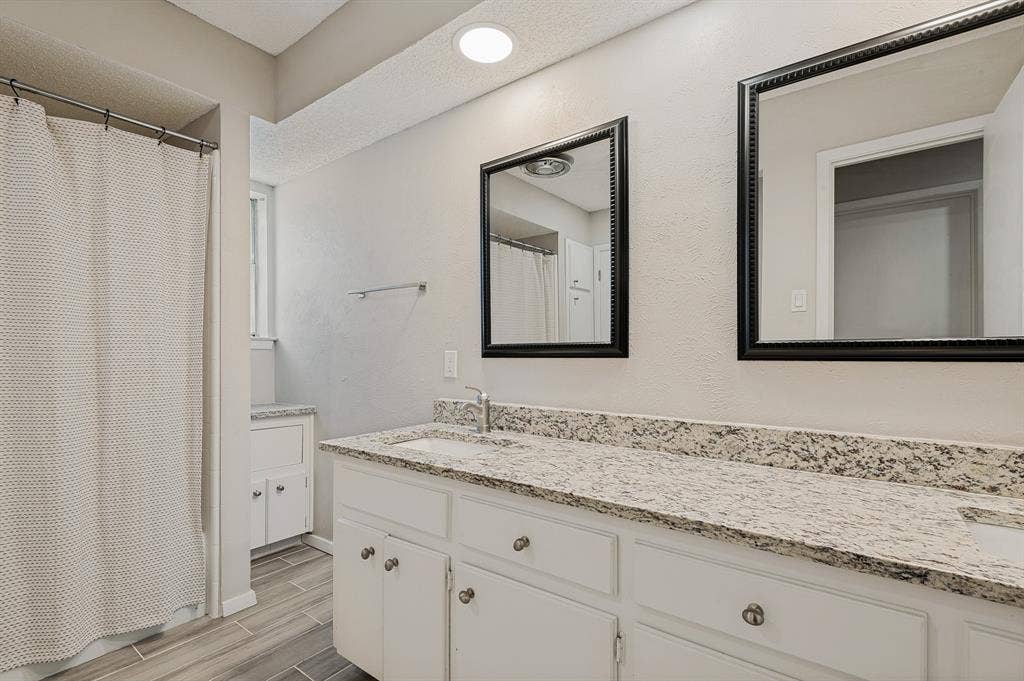 404 Green River Trail, Fort Worth, TX 76103 Bathroom featuring a dual vanity with light-toned granite countertops, under-mount sinks, and chrome faucets