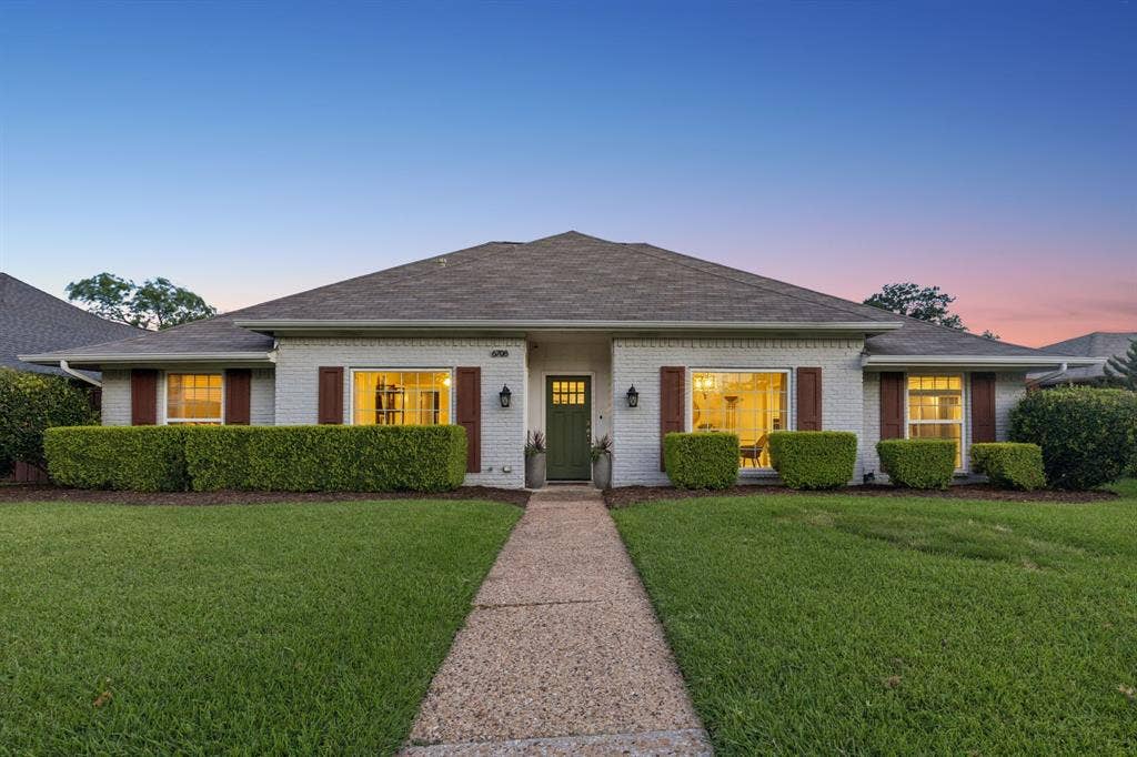 6708 McCallum Boulevard, Dallas, TX 75252 White brick exterior with a dark roof and green front door