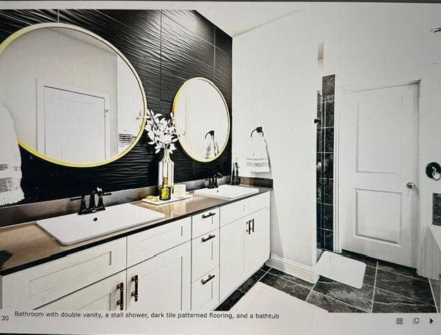 4220 Calla Drive, Forney, TX 75126 Modern bathroom featuring a double vanity with white cabinetry and dark countertops, accented by two gold-framed circular mirrors