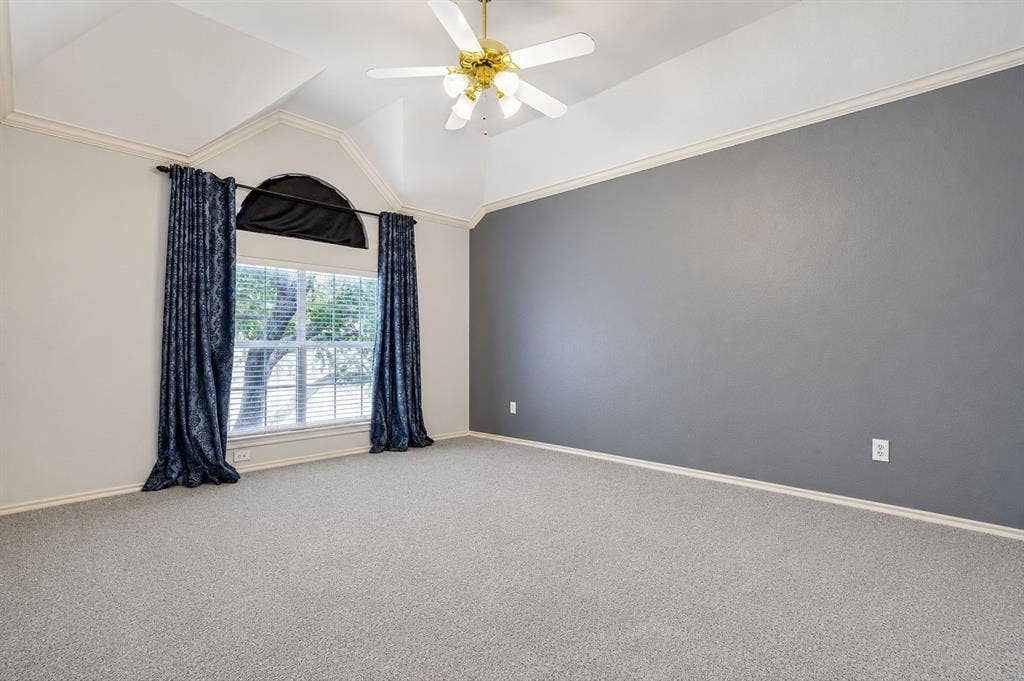 110 Falcon Creek Drive, McKinney, TX 75072 Vaulted ceiling room featuring a large window with an arched transom, light gray carpeting, and a ceiling fan