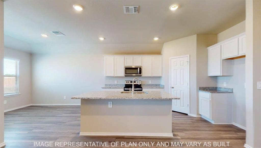 10325 Altair Drive, Waco, TX 76708 Open concept kitchen featuring a central island with a sink, white cabinetry, integrated stainless steel microwave, and wood-finish flooring