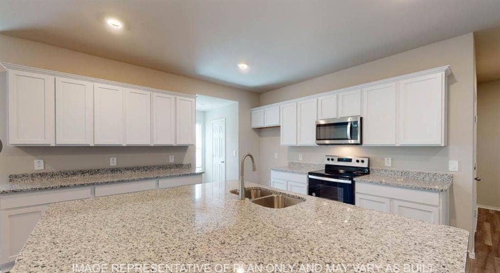 10317 Altair Drive, Waco, TX 76708 Kitchen featuring an expansive island with a dual basin stainless steel sink, light-toned granite countertops, white shaker cabinetry, stainless steel microwave, and built-in electric range