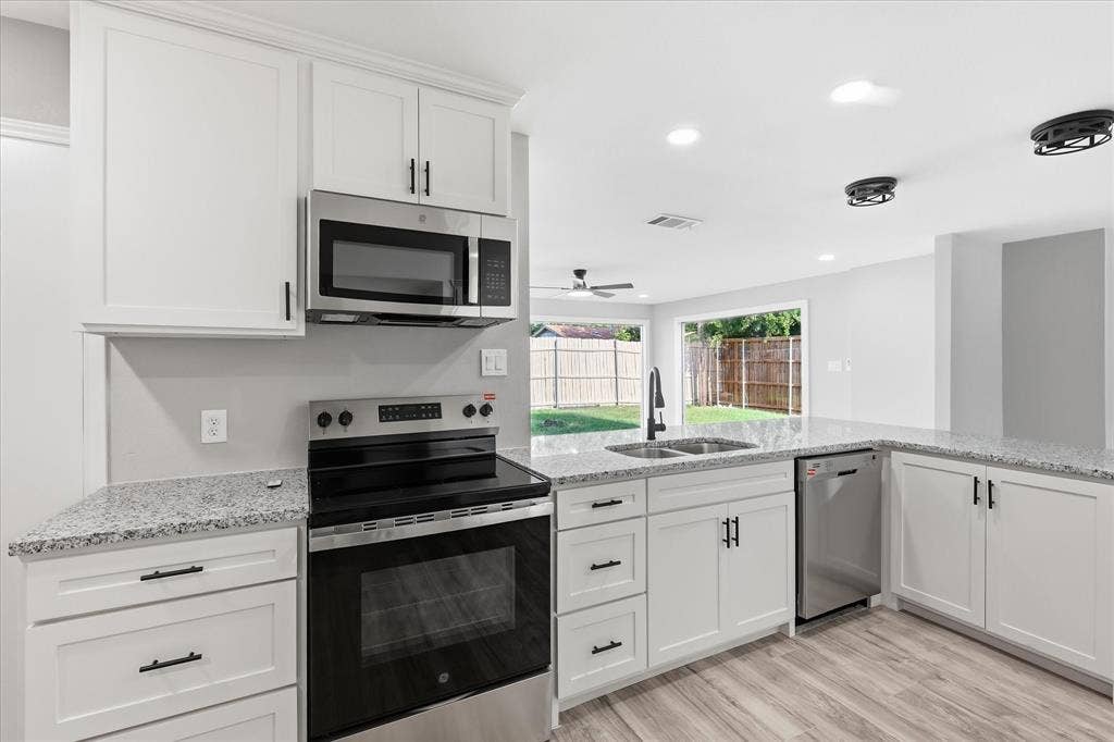857 Twilight Trail, Grapevine, TX 76051 Modern kitchen featuring white shaker cabinetry, stainless steel appliances, speckled countertops, wood-finish flooring, and recessed lighting