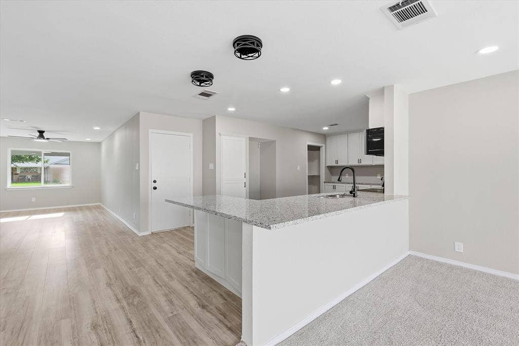 857 Twilight Trail, Grapevine, TX 76051 Open-concept kitchen and living area featuring a breakfast bar with a stone countertop, light wood-finish flooring, recessed lighting, and a ceiling fan