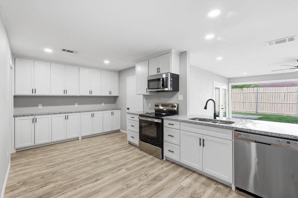 857 Twilight Trail, Grapevine, TX 76051 Contemporary kitchen featuring white cabinetry, light-toned wood-finish flooring, recessed lighting, stainless steel appliances, and granite-style countertops