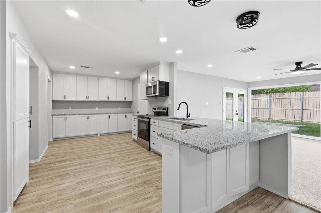 857 Twilight Trail, Grapevine, TX 76051 Expansive kitchen featuring white shaker cabinetry, light-toned wood-finish flooring, and a large island with a speckled countertop and integrated sink