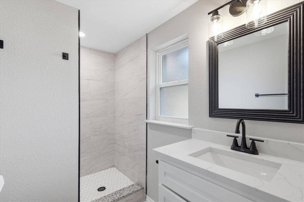 857 Twilight Trail, Grapevine, TX 76051 Contemporary bathroom featuring a white vanity with an integrated sink, a dark framed mirror, and a three-light fixture