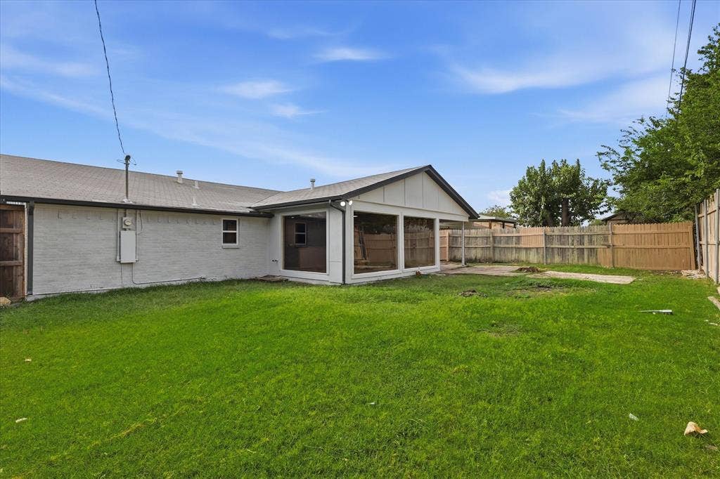 857 Twilight Trail, Grapevine, TX 76051 Spacious backyard featuring a sunroom addition with large windows, a fenced perimeter, and a substantial lawn area