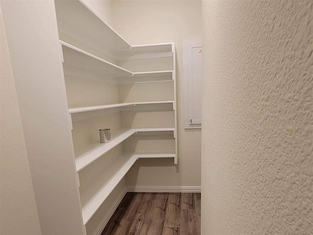 11346 Sugarlands Drive, Frisco, TX 75035 Spacious pantry featuring extensive white shelving, a natural wood-finish floor, and light-toned walls