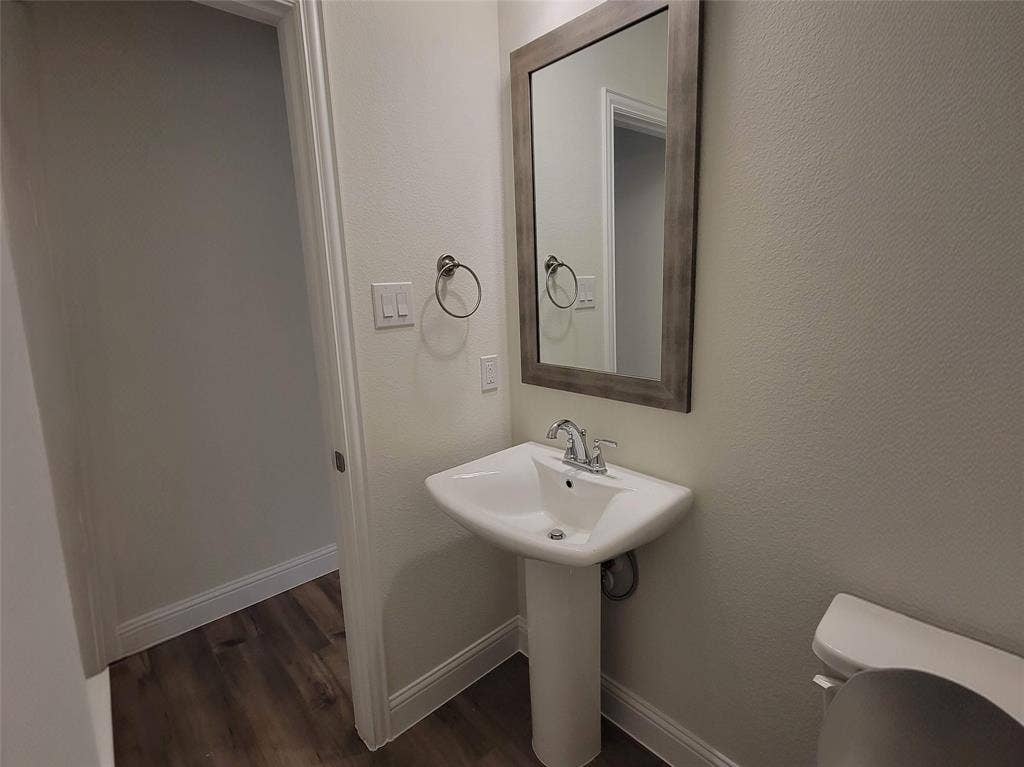 11346 Sugarlands Drive, Frisco, TX 75035 Pedestal sink with chrome faucet, framed mirror, and wood-finish flooring