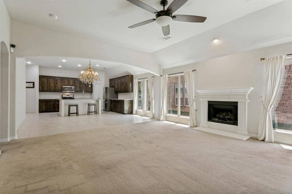 Spacious living area featuring a central fireplace with a white mantel, multiple large windows, and a ceiling fan