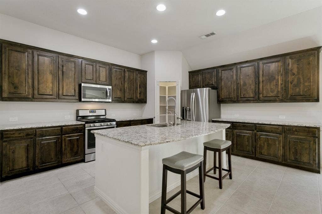 Kitchen featuring dark wood-finish cabinetry, light-toned countertops, and stainless steel appliances