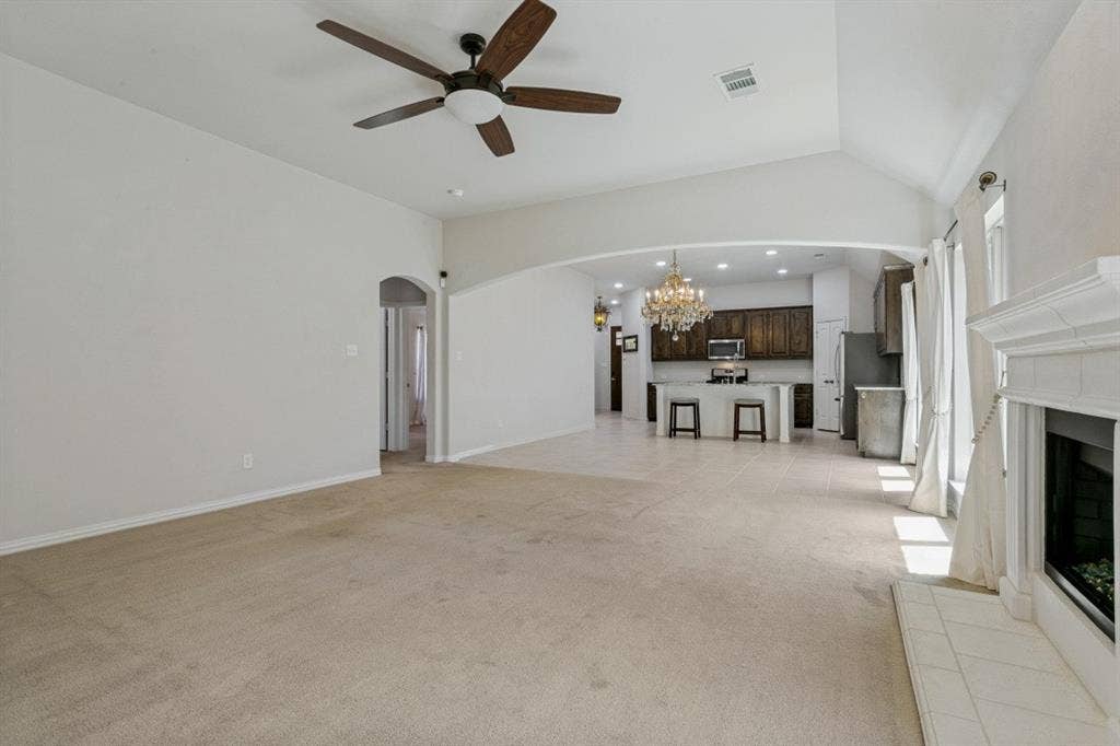 Spacious living area featuring a vaulted ceiling and a wood-bladed ceiling fan