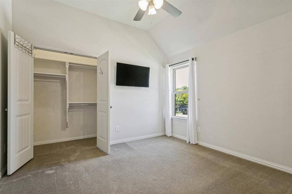 Bedroom with vaulted ceiling, ceiling fan, and carpeted flooring