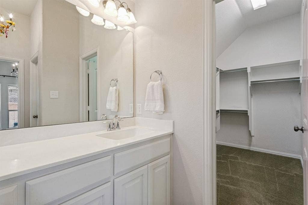 Bathroom vanity with a single basin sink, white cabinetry, and a light-toned countertop