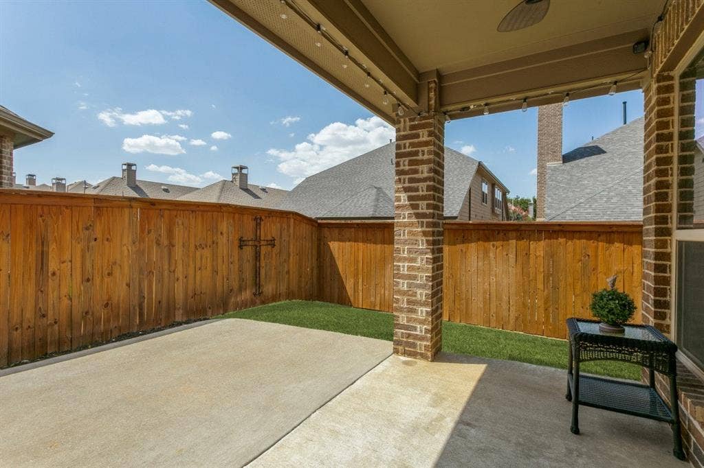 Covered patio featuring a ceiling fan, string lighting, and brick columns