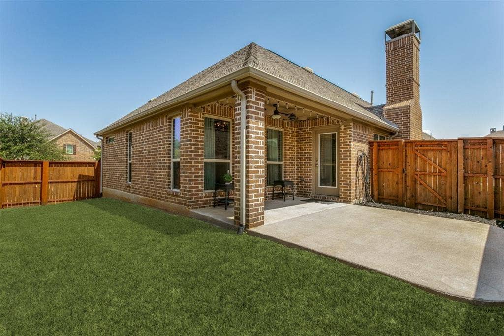 Brick exterior with a covered patio, expansive concrete slab, and wood privacy fencing