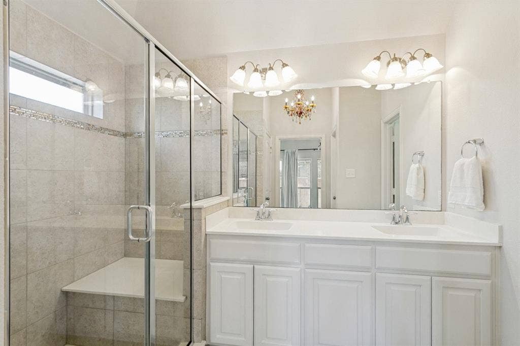 Spacious bathroom featuring a dual vanity with white cabinetry, a large frameless mirror, and overhead lighting