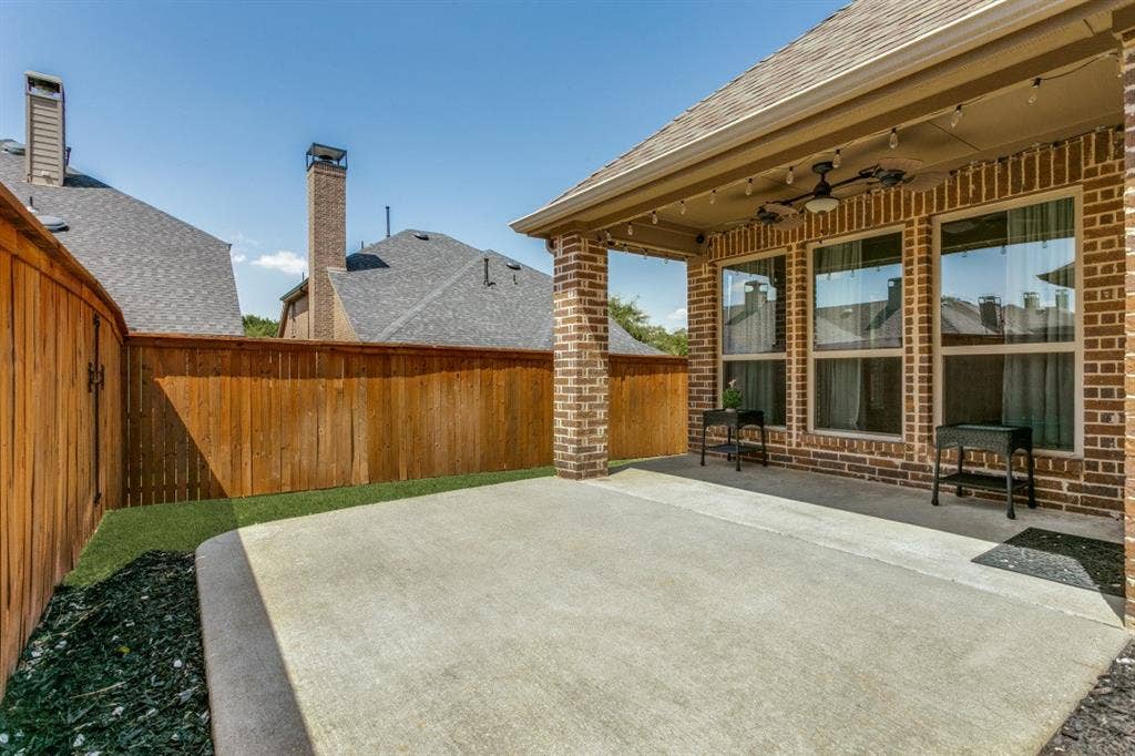 Spacious concrete patio with a covered outdoor living area featuring a ceiling fan and string lighting