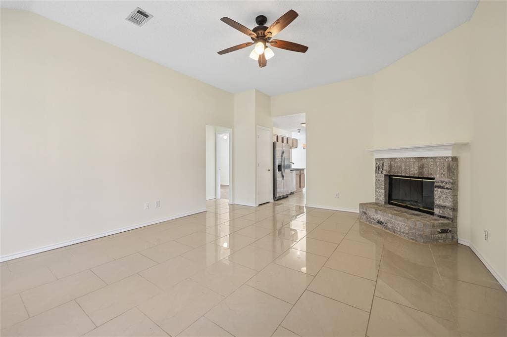 113 Bridlegate Drive, McKinney, TX 75069 Living area featuring high ceilings, large-format tile flooring, a stone-surround fireplace with a mantel, and a ceiling fan