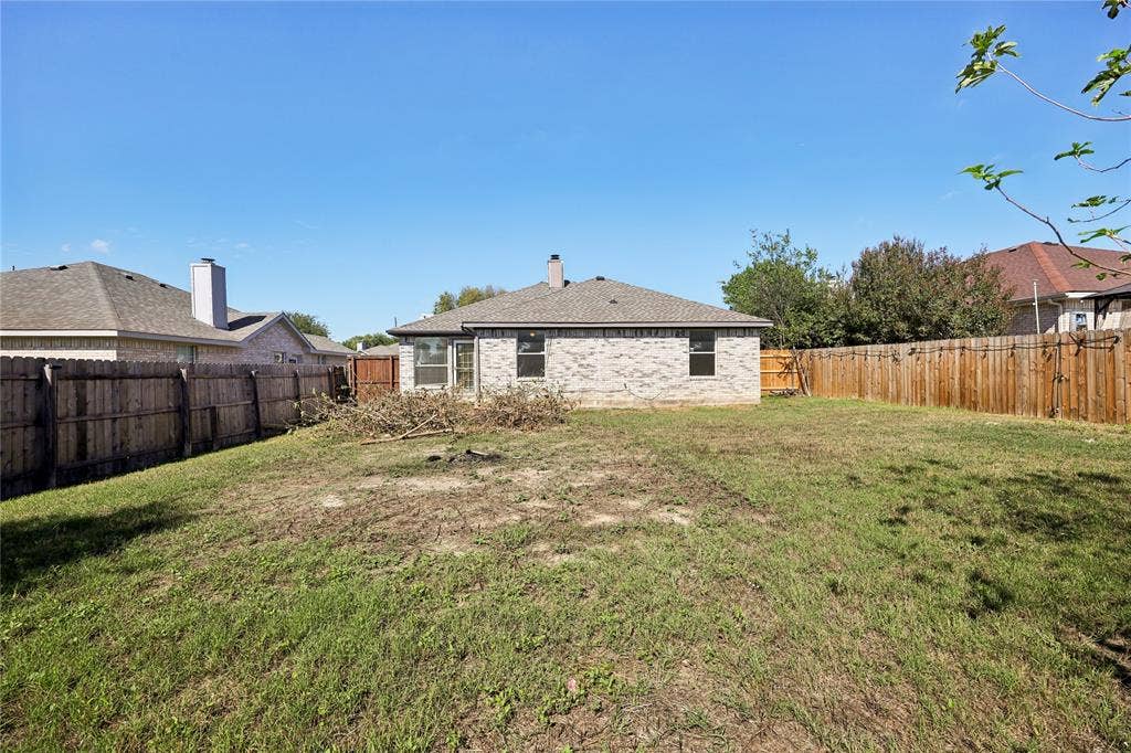 113 Bridlegate Drive, McKinney, TX 75069 Rear exterior featuring a brick facade, roof chimney, and enclosed wooden perimeter fencing