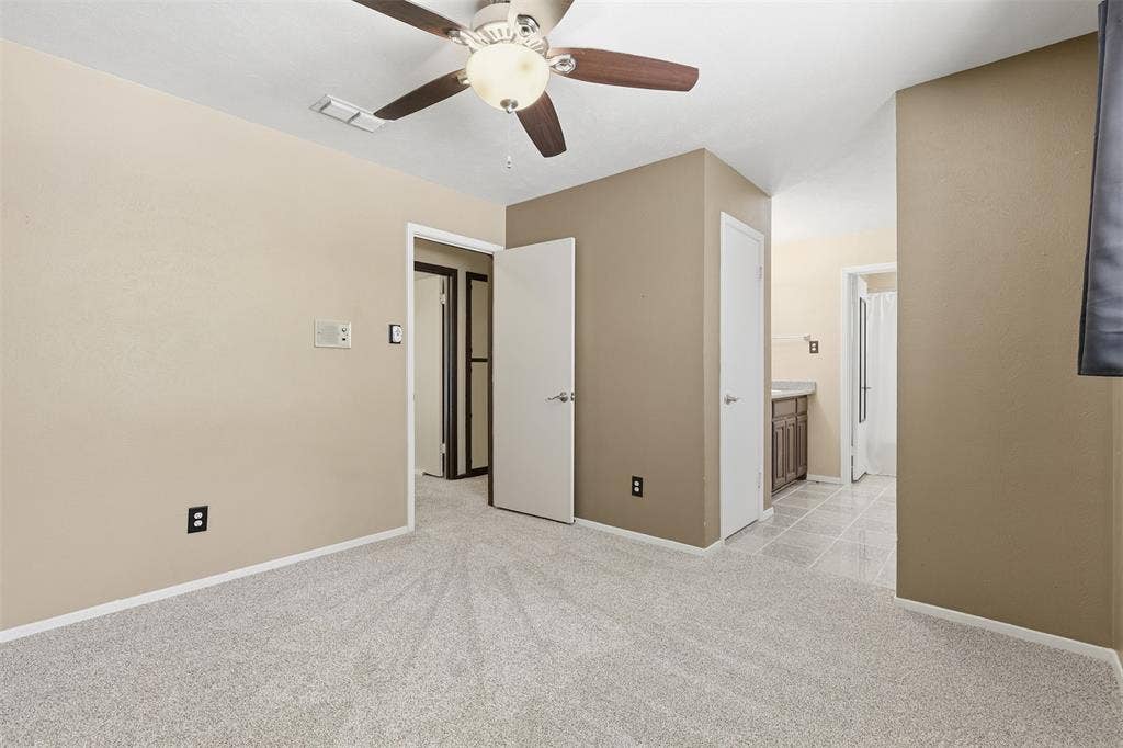 3702 Hastings Drive, Arlington, TX 76013 Additional view of the primary bedroom highlighting its ceiling fan, neutral colors, new carpet, and direct access to the adjoining bathroom area
