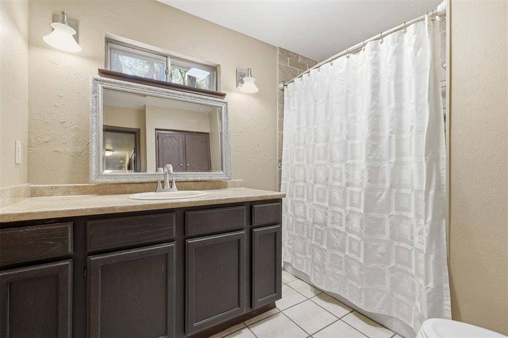 3702 Hastings Drive, Arlington, TX 76013 Full bathroom with a spacious vanity, decorative mirror, tile flooring, window, and tub-and-shower combination