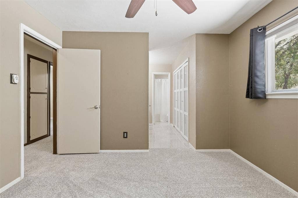 3702 Hastings Drive, Arlington, TX 76013 Primary bedroom offers natural light, new carpet, a ceiling fan, and convenient access to the bathroom and multiple closets