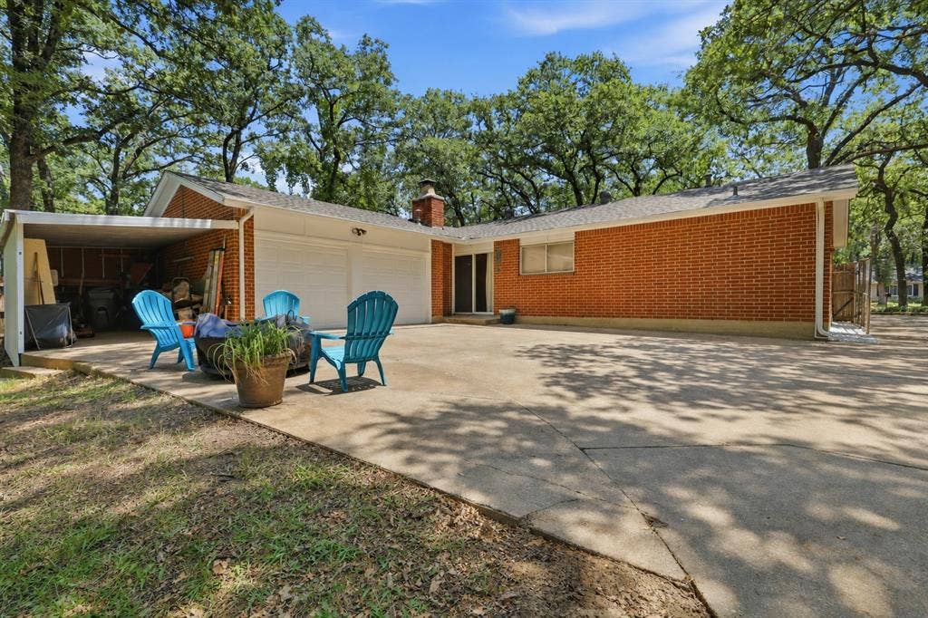 3702 Hastings Drive, Arlington, TX 76013 Expansive backyard patio and driveway provide abundant outdoor living space beneath mature shade trees, with convenient access to the attached two-car garage