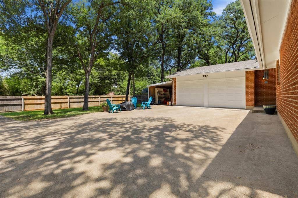 3702 Hastings Drive, Arlington, TX 76013 Expansive backyard patio and driveway provide abundant outdoor living space beneath mature shade trees, with convenient access to the attached two-car garage