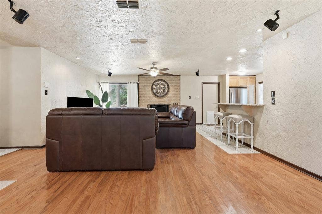 3702 Hastings Drive, Arlington, TX 76013 Living room with wood flooring, ceiling fan, generous seating space, and an open flow toward the kitchen and dining areas