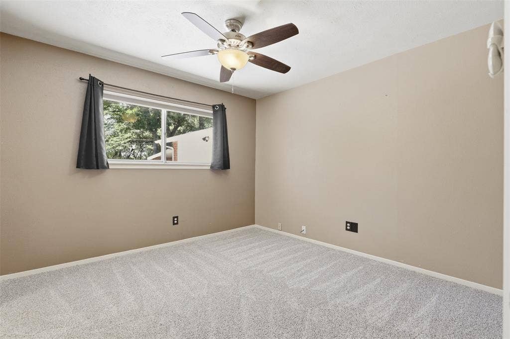 3702 Hastings Drive, Arlington, TX 76013 Primary bedroom with new carpet installed July 2026, ceiling fan, natural light, and convenient access to the bathroom and storage area